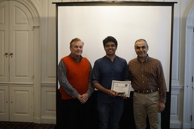 recipient holds award while standing between professors