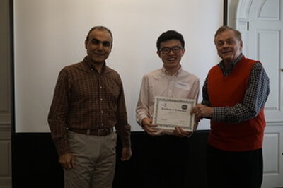 recipient holds award while standing between professors